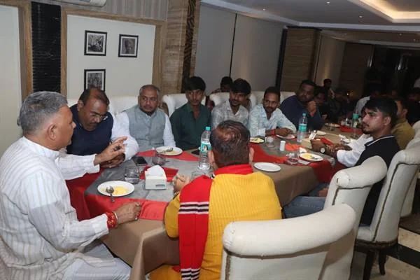 भोजन की मेज के चारों ओर बैठे लोगों का समूह आपस में बातचीत करते हुए