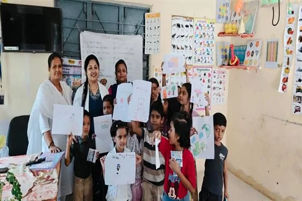 कक्षा में महिलाएं और बच्चे स्वास्थ्य जागरूकता गतिविधि के दौरान चित्र और पर्चे दिखाते हुए
